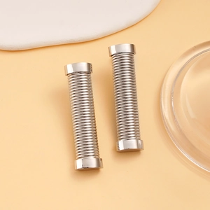 Macro detail of silver stainless steel cylinder earrings with spiral textured finish