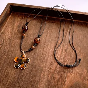 Vintage resin flower pendant necklace with amber texture and gold rim on wood tray