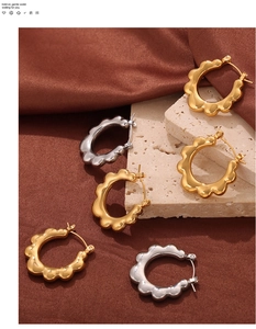 Detail view of wavy gold and silver hoop earrings on a velvet background texture