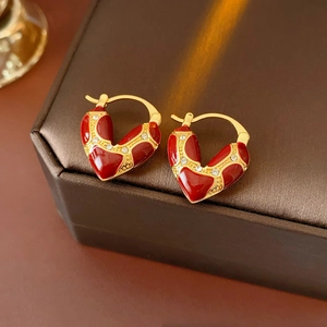 Detailed macro view of heart earrings with red enamel and crystals on brown fabric box