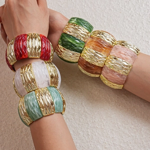 Close-up of colorful resin and textured gold metal stretch bracelets on a wrist