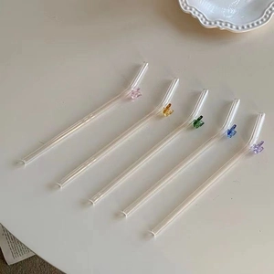 Detailed view of five colorful glass butterfly ornaments on curved reusable drinking straws