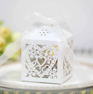 Detail of white laser-cut heart candy box with organza ribbon on a decorative plate