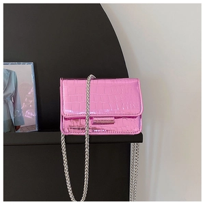Detail of pink faux leather crossbody bag with crocodile texture and silver chain strap