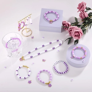 Detail of purple and white clay bead jewelry set with gold butterfly charms and letter beads