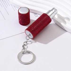Detail of red rhinestone encrusted perfume atomizer with metal keychain attachment