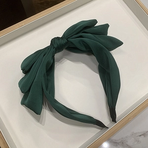 Detail of dark green triple-layered bow headband with matte silk fabric texture