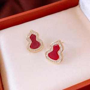 Macro view of gold gourd stud earrings with red enamel and white zircon stones