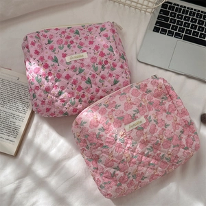 Close-up of quilted floral cosmetic bags with pink patterns and brand label detail