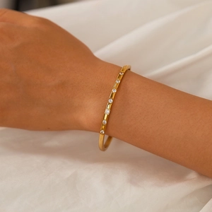 Detail of elegant gold bangle with round cubic zirconia on wrist with soft white background