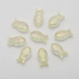Macro shot of 9 rainbow plated fish-shaped crystal beads arranged in a circle on white background