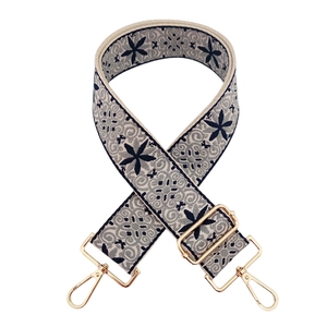 Detail of navy and grey floral embroidery on wide bag strap with gold metal hooks