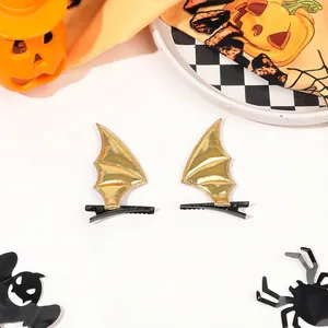Close-up of golden bat wing hair clips for Halloween with festive pumpkin background