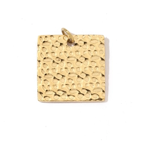 Close-up of a square gold vintage pendant with a hammered texture and integrated bail