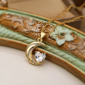 Macro detail of 18K gold plated crescent moon and heart zircon pendant on necklace