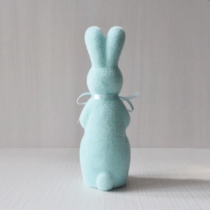 Detail of cute blue flocked Easter rabbit ornament with matching ribbon on wooden surface