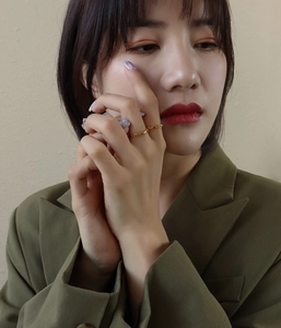 Detail shot of a minimalist 18K gold chain ring on a finger with olive green suit
