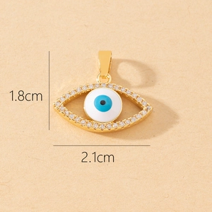 Detail view of a gold evil eye pendant with tiny zircons measuring 1.8cm by 2.1cm