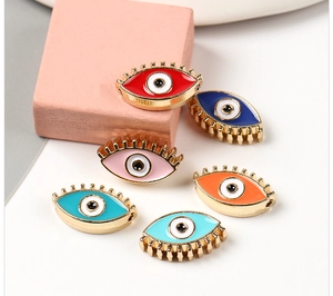 Detailed view of colorful evil eye enamel charms with gold eyelashes for DIY jewelry