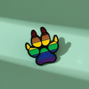 Rainbow enamel animal paw print metal pin brooch with colorful stripes on green background