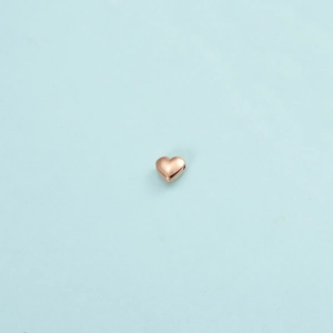 Polished rose gold heart charm with 1mm hole on a minimalist blue background