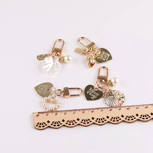 Macro view of four gold-plated pearl charms with heart and shell details and ruler