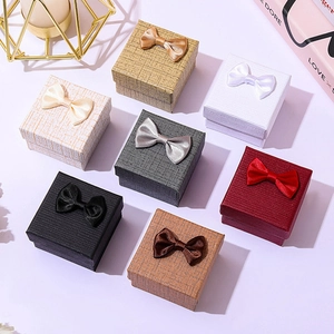 Textured square jewelry gift boxes with bows in multiple colors on a purple background