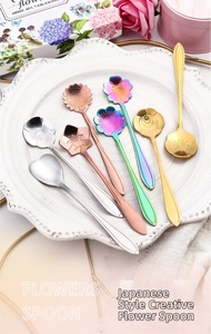 Set of 7 floral stainless steel stirring spoons in multiple metallic finishes on white plate