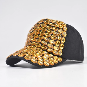 Dettaglio di strass arancioni incastonati a mano su un cappello da baseball in cotone nero