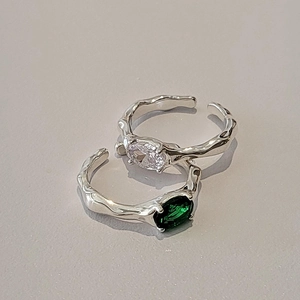 Close-up of irregular liquid metal rings with green and white zircon stones