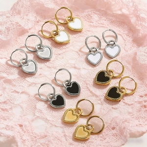 Detail of heart charm hoop earrings in gold and silver finish on pink lace fabric