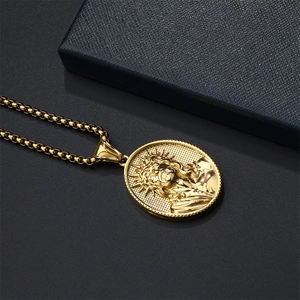 Macro detail of golden Jesus relief pendant on box chain over black matte surface