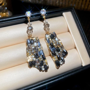 Macro detail of geometric square drop earrings with black crystals on velvet tray