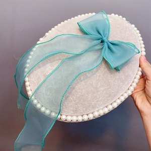 Detailed view of handmade light grey hair clip with pearls and turquoise organza bow