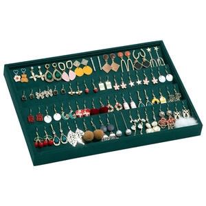 Vintage dark green velvet jewelry tray displaying various earrings on white background