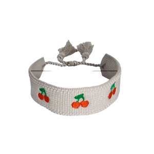 Handmade woven bracelet with red cherry embroidery and gray tassels, white background