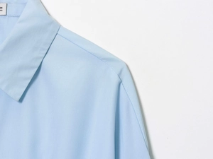 Detail of light blue shirt showing a classic pointed collar and neat stitching on shoulder