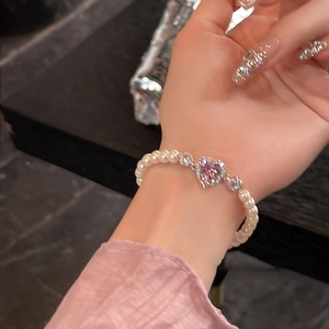 Vue macro d'un bracelet en perles avec un cœur en zircon rose et détails brillants
