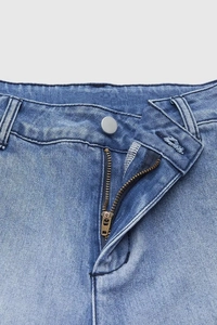 Gros plan détaillé de la taille en jean bleu clair avec fermeture éclair en métal et bouton YKK