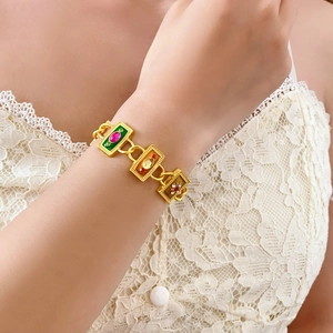 Close-up of a vintage gold bracelet with colorful enamel floral and gem-set rectangular links