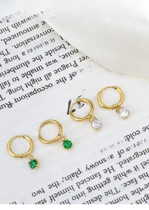 Detailed view of titanium steel gold earrings with clear and emerald cubic zirconia
