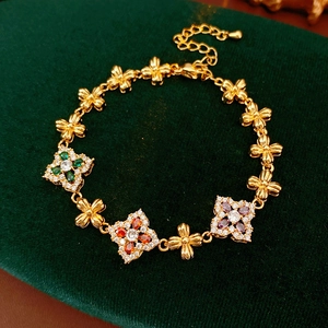 Detalle de pulsera vintage dorada con flores de circón de colores sobre terciopelo
