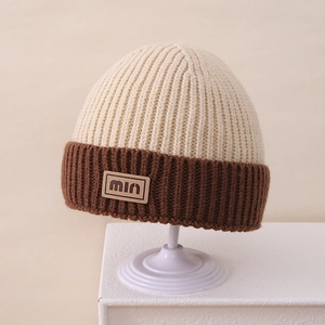 Close-up of contrast-color knit beanie with min leather patch and thick ribbed texture
