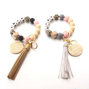 Detailed macro view of mama silicone and wood bead wristlet with tassels and gold hardware