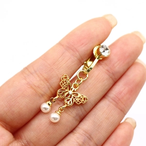 Vue détaillée d'un clip papillon doré avec strass et perles blanches suspendues