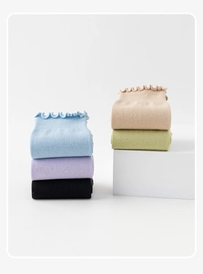 Close-up of five pairs of ruffled cotton yoga socks in assorted pastel colors on white