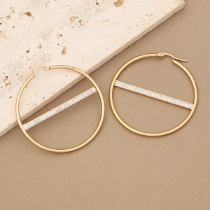 Golden geometric hoop earrings with sparkling zircon bar design on stone background