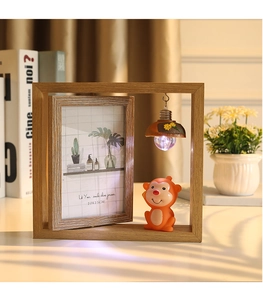 Gros plan d'un cadre photo rotatif en bois de 6 pouces avec figurine de singe et veilleuse