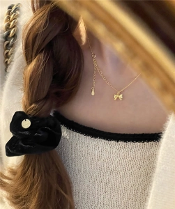 Detail of s925 silver bow necklace and velvet hair tie on model for a sweet look