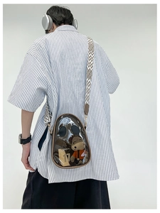 Close-up of transparent PVC crossbody bag with brown trim and geometric wide strap
